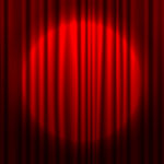Red theater curtain partially open with spotlight on stage